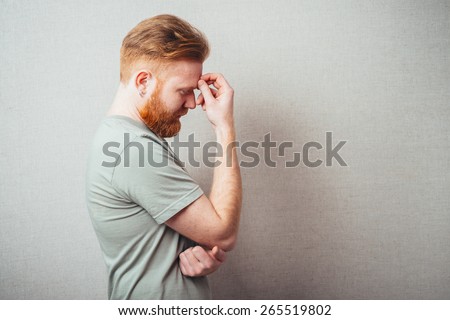 Portrait of the thinking red man looks up with hand near face