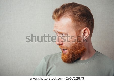 Profile of Young hipster red bearded Man standing against grey background