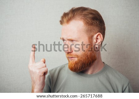 Handsome bearded  man in blue collar shirt smiles and points with finger