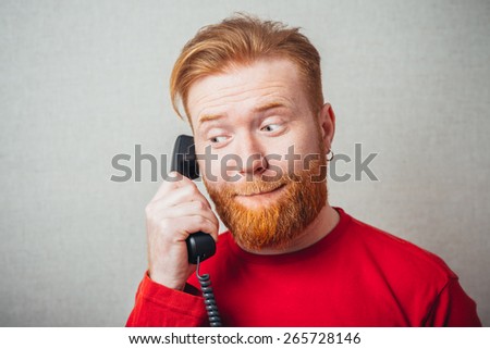 closeup portrait of Young hipster red bearded Man talking on corded retro phone