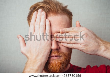 Young hipster red bearded Man closes his eyes with his hands