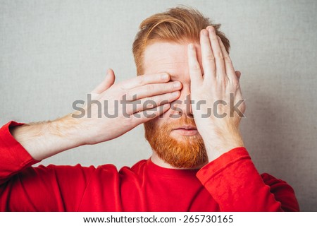 Young hipster red bearded Man closes his eyes with his hands