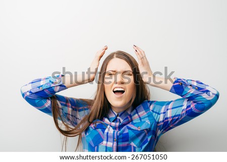 Young woman screaming with hands on head against white background