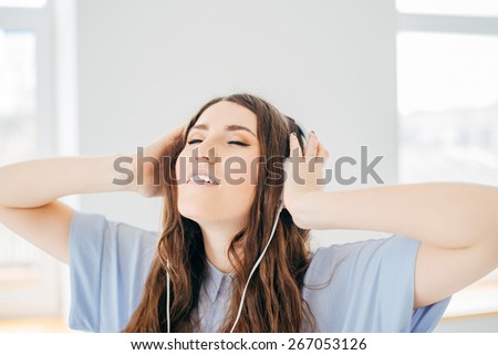 Beautiful girl listen music near the window, in house