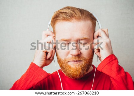 young man in headphones with closed eyes listening to the unpleasant or out of tune music