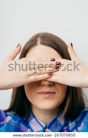 on white background young girl closes eyes with her hands