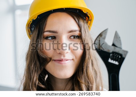 young girl in a helmet holding a wrench