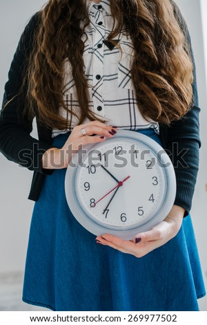 Confident Friendly Young Caucasian  Woman Holding A Large Clock In Hands Showing The Success And Joy Of Good Office Timekeeping In A Happy Hour Concept