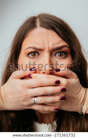 beautiful brunette girl covers her mouth with her hands