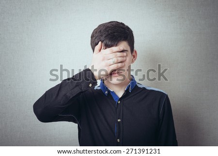 Portrait of a handsome man covering his eyes with hand in studio