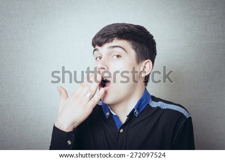 Young man yawns and covered his mouth with hand