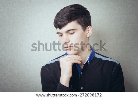 Handsome young man pensive and looking at side isolated on a gray background