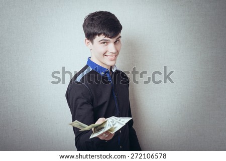 Portrait of smiling young man holding fanned US paper currency
