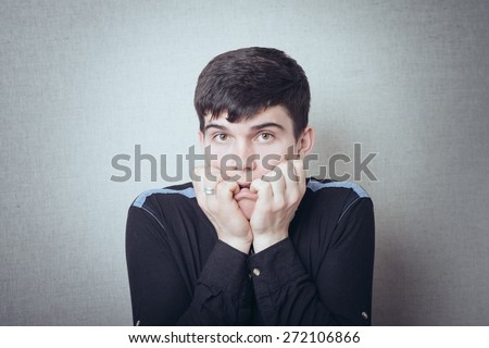 portrait of brunette man scared and keeps finger in mouth