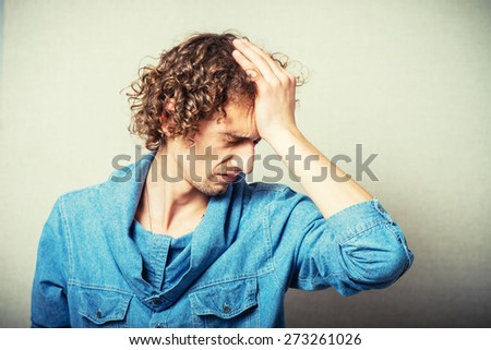 curly man made a mistake, and clings to his forehead hands