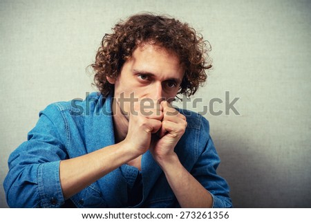 curly-haired man praying, clasped his hands together