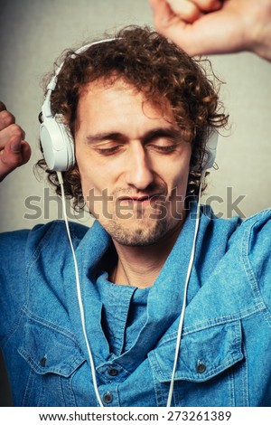 curly man listening to music on headphones white, dancing