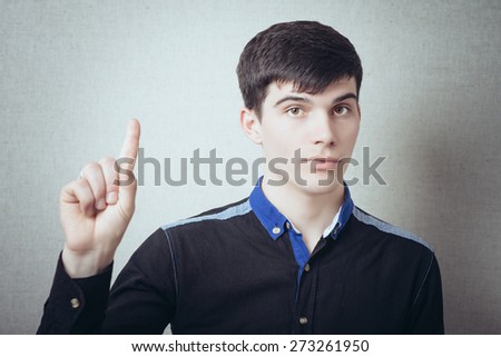 Young man pointing finger up the idea. On a gray background