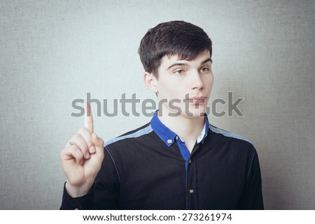 Young man pointing finger up the idea. On a gray background