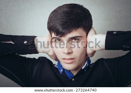 Man covers his ears hands, a gesture too loud, I do not want to hear quieter. On a gray background