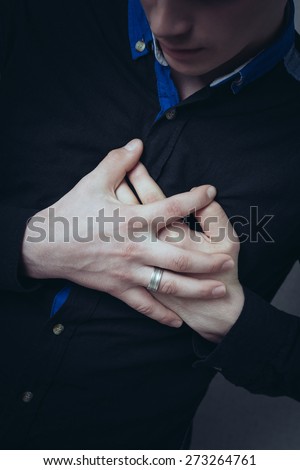 Man hands on his chest, a sore heart. Gesture heart aches attack. On a gray background