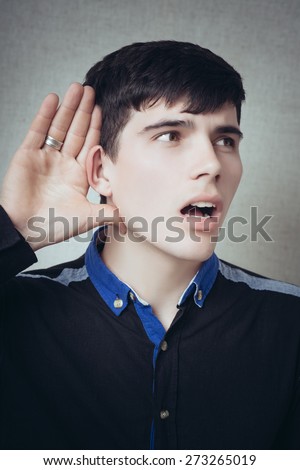 A man with his hand near his ear. Gesture can not hear without listening, talking louder. On a gray background