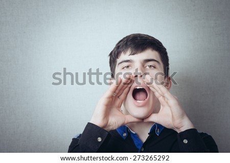 A man with his hands near his mouth. Gesture to call someone shout, speak loudly. On a gray background