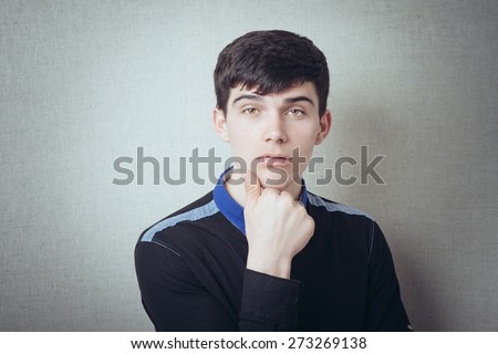 Man thinks with his head on his fist. On a gray background.
