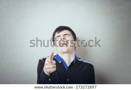 Young confident teenager guy smiling and pointing at camera
