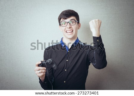 Happy young man in winning pose wearing shirt holding video game joystick. Mask included