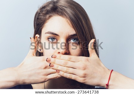 blue-eyed brunette girl covers her mouth with her hands