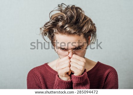 The man covered his face with his fists, frustrated. On a gray background.