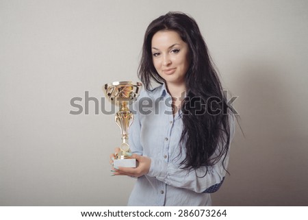 portrait of happy businesswoman keeping golden cup. Concept of victory and success