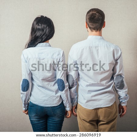 Back view young couple  hug. beautiful friendly girl and guy together. Rear view. boy and girl  couples face with his hands in his pockets and looking at something interesting