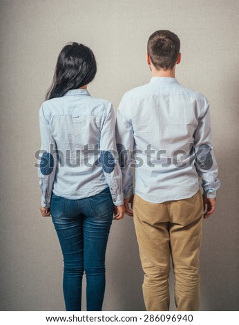 Back view young couple  hug. beautiful friendly girl and guy together. Rear view. boy and girl  couples face with his hands in his pockets and looking at something interesting