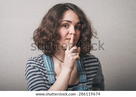 Beautiful woman with secret holding finger over lips.
