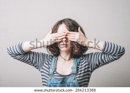 The woman closed her eyes with her hands. On a gray background.