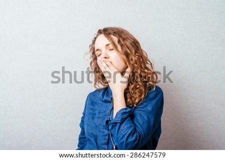 The woman yawns. Gray background