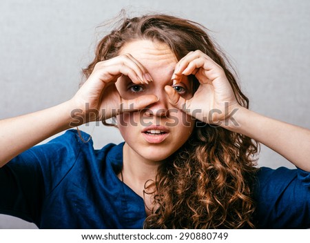 Pretty young woman looking for something with wide open eyes and imaginary binocular