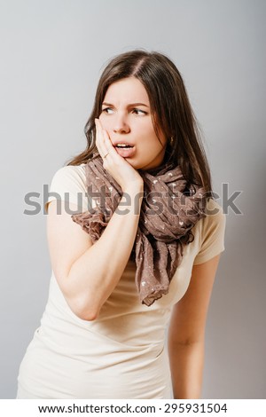 Young woman condemned looks away. On a gray background.