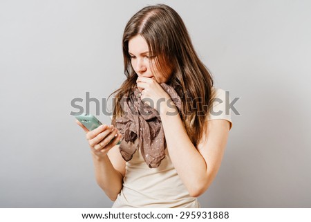 Young woman reading the sad news on the phone. On a gray background.
