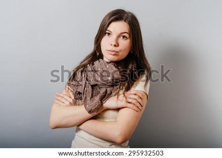 Young woman folded her arms. On a gray background.