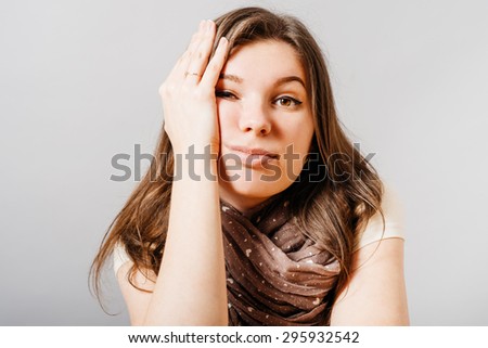 Young woman listens to a boring story. On a gray background.