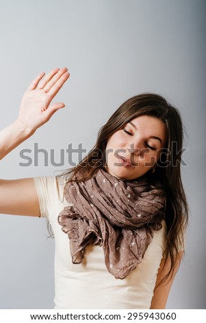 Young woman closed her eyes, shows displeasure leave me alone. On a gray background.