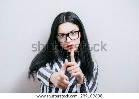 Woman in glasses showing thumbs come forward. On a gray background.