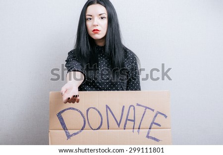 A woman shows a sign on cardboard donate. On a gray background.