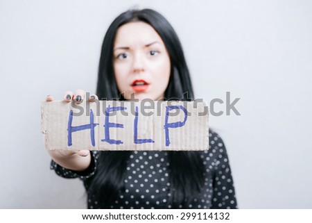A woman shows a sign on cardboard help. On a gray background.
