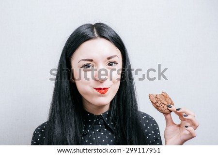 Beautiful woman laughing and eating cookies. On a gray background.