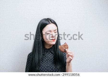 Beautiful woman laughing and eating cookies. On a gray background.