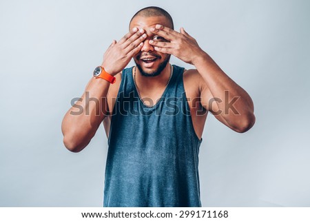 The man closed his eyes African hands, looking through his hands. On a gray background.